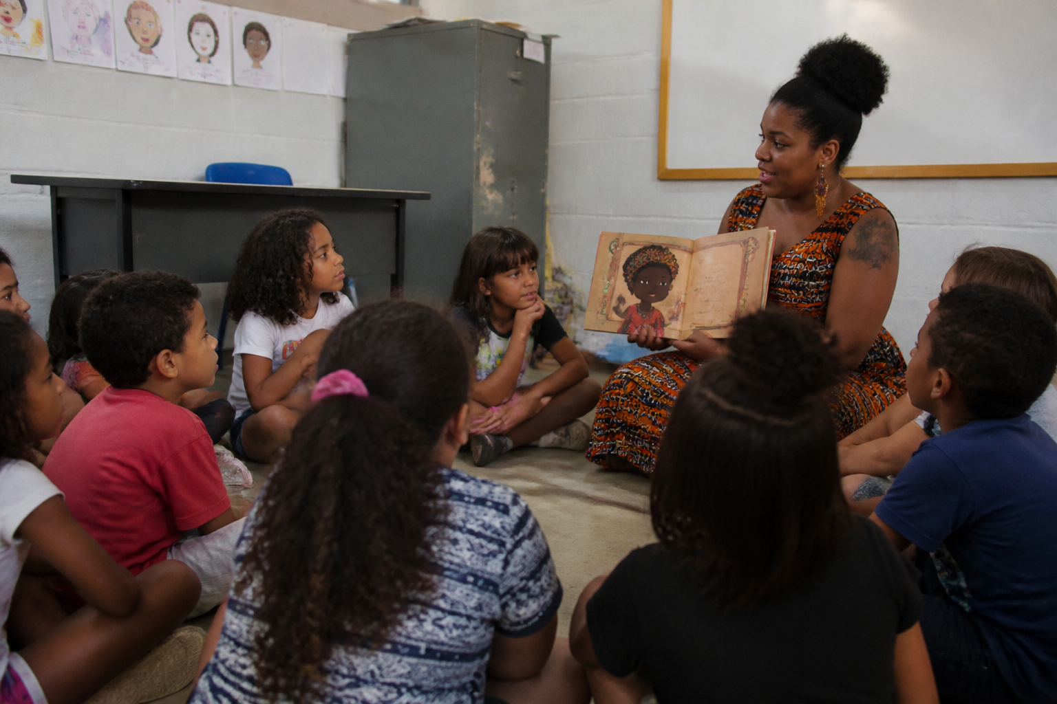 Professora negra lendo um livro para crianças sentadas em roda
